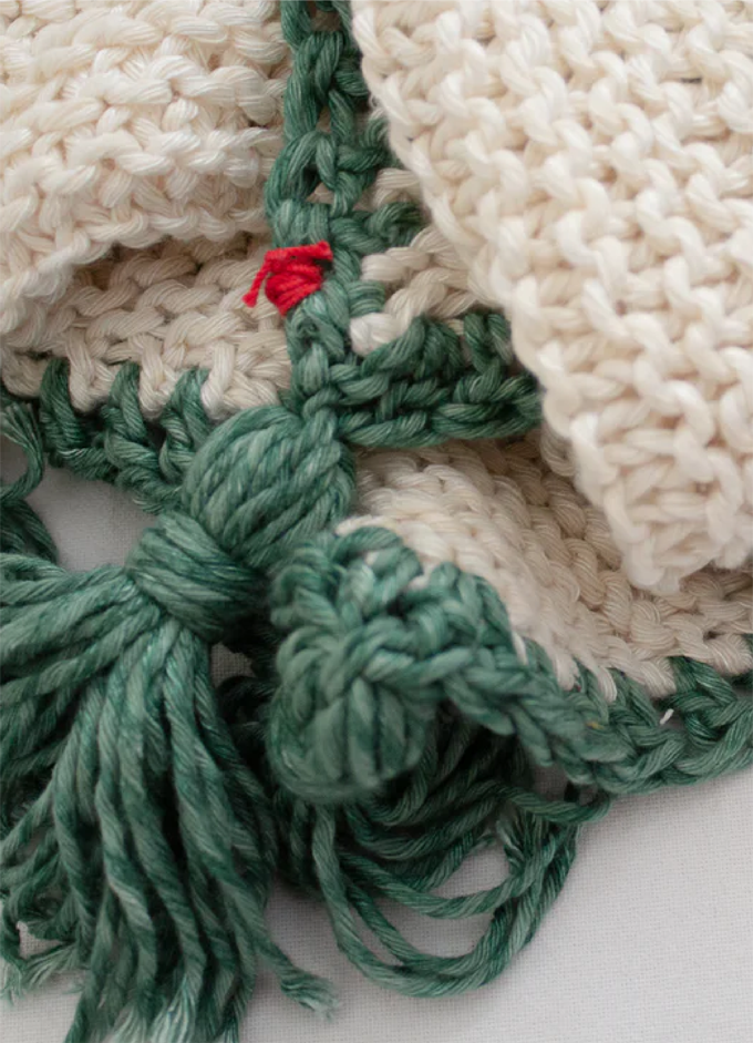 Penelope D handmade chunky-knit cream challah cover with green edging and tasselled ends