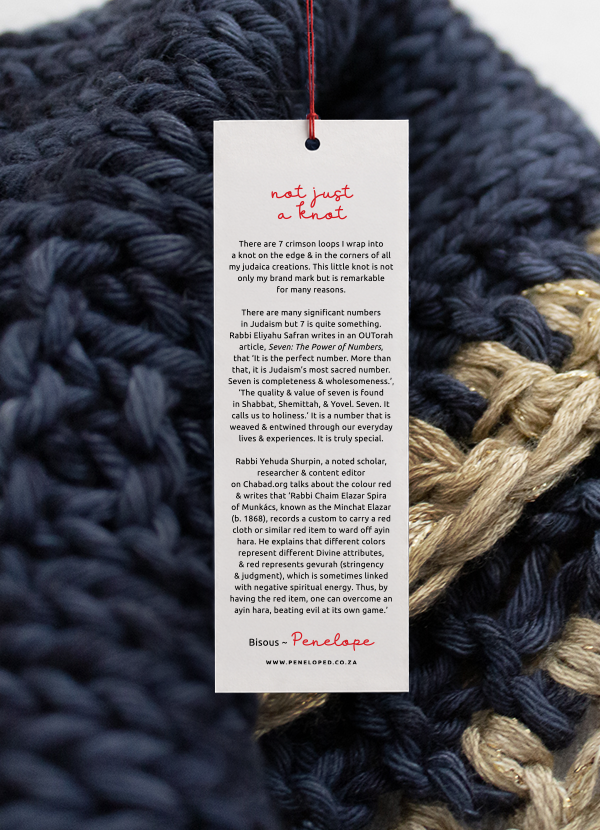 Penelope D story swing tag attached to a navy chunky-knit challah cover
