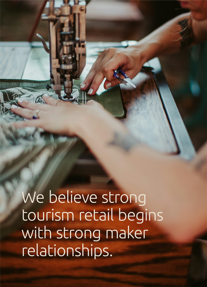 Reign On Africa maker embroidering fabric with the tagline We believe strong tourism retail begins with strong maker relationships.